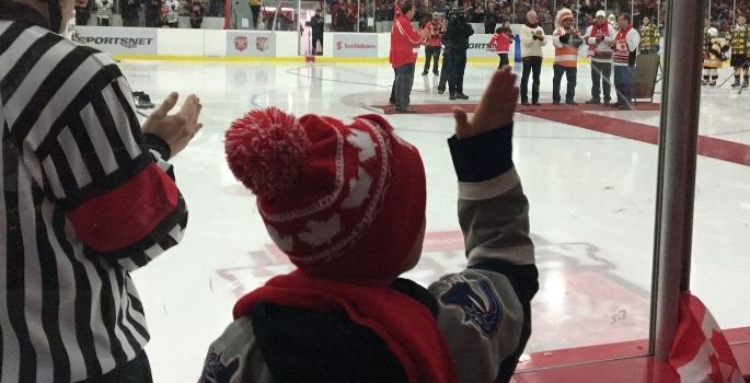 boy waving at hockey players on the ice
